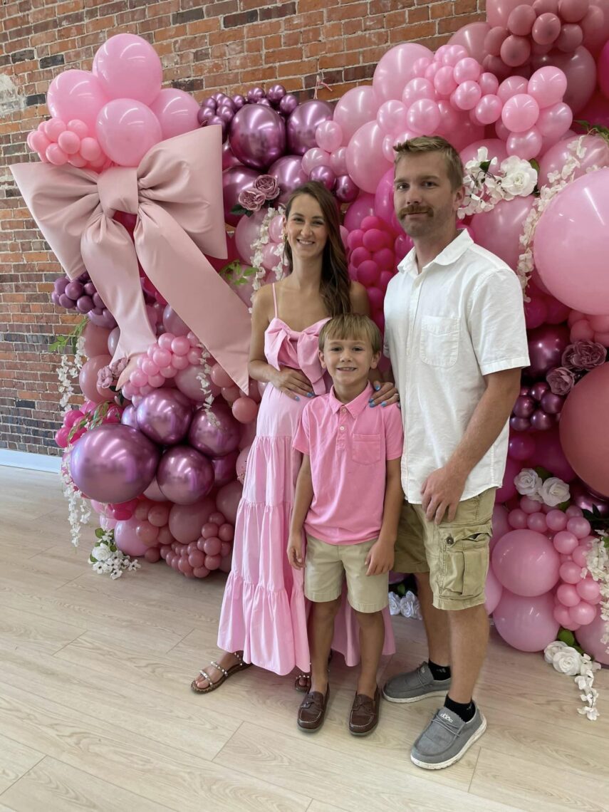 family photo in front of pink balloon wall